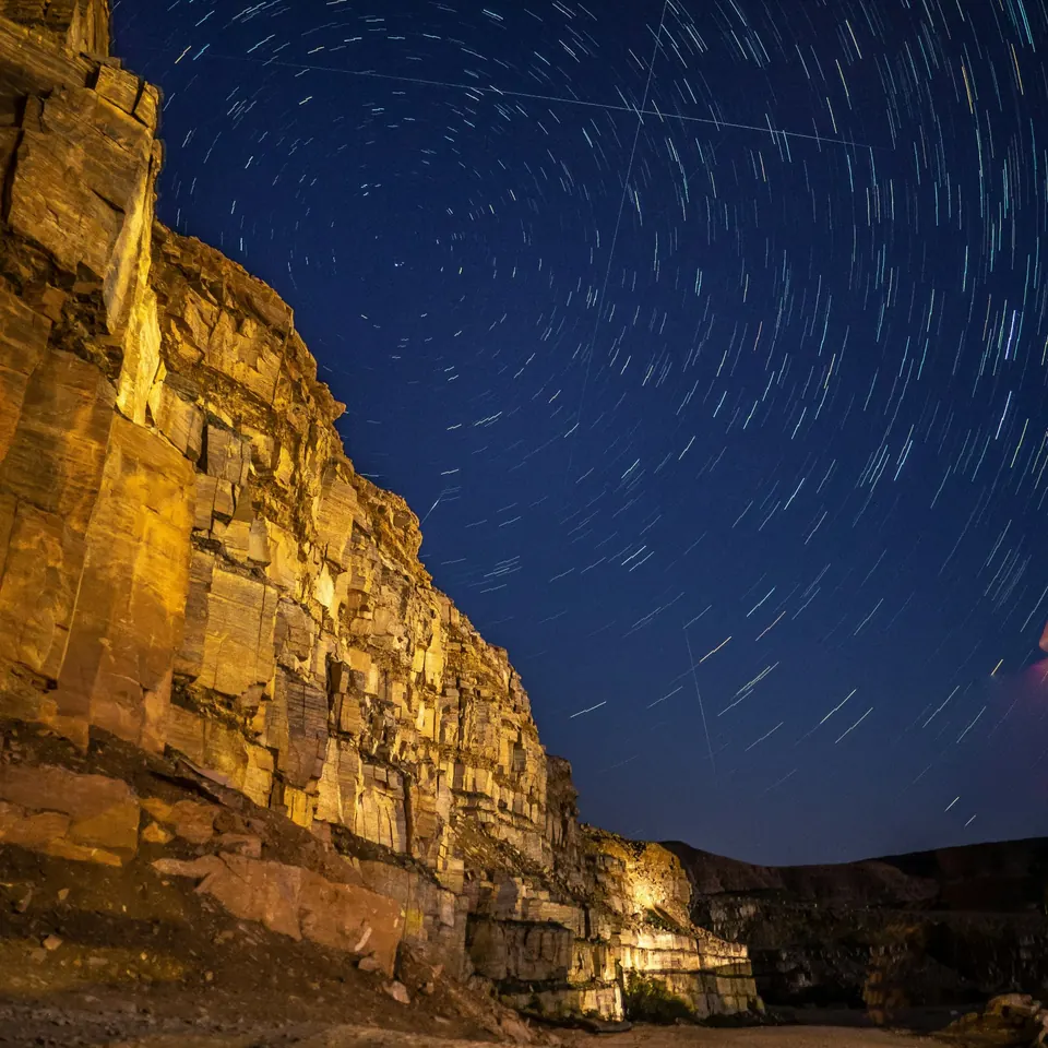 La nuit tombe sur une falaise du cratère Ramon, sous un ciel strié par la course des étoiles